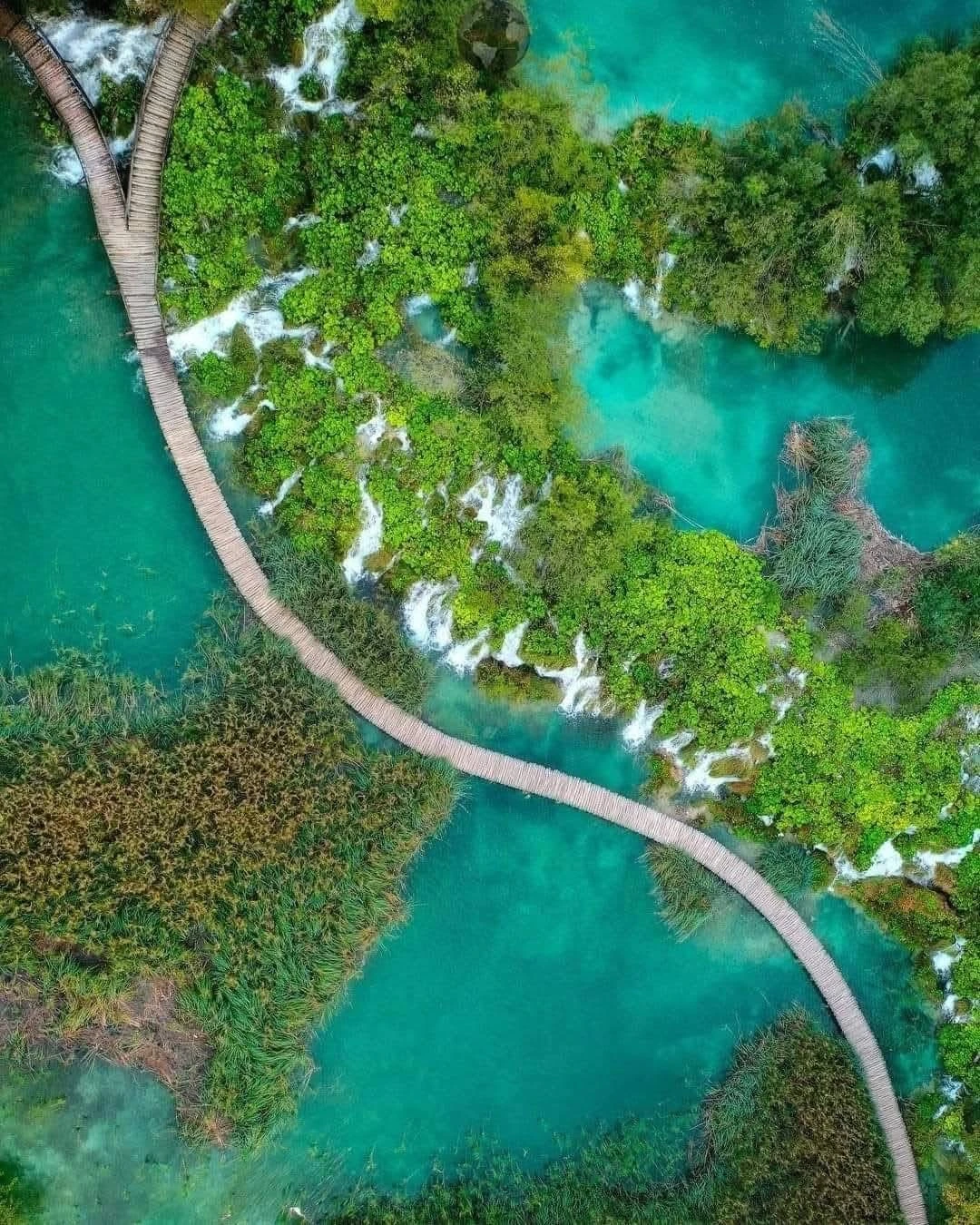 Aerial view of the wooden boardwalks winding above the turquoise lakes and waterfalls of Plitvice Lakes National Park, Croatia